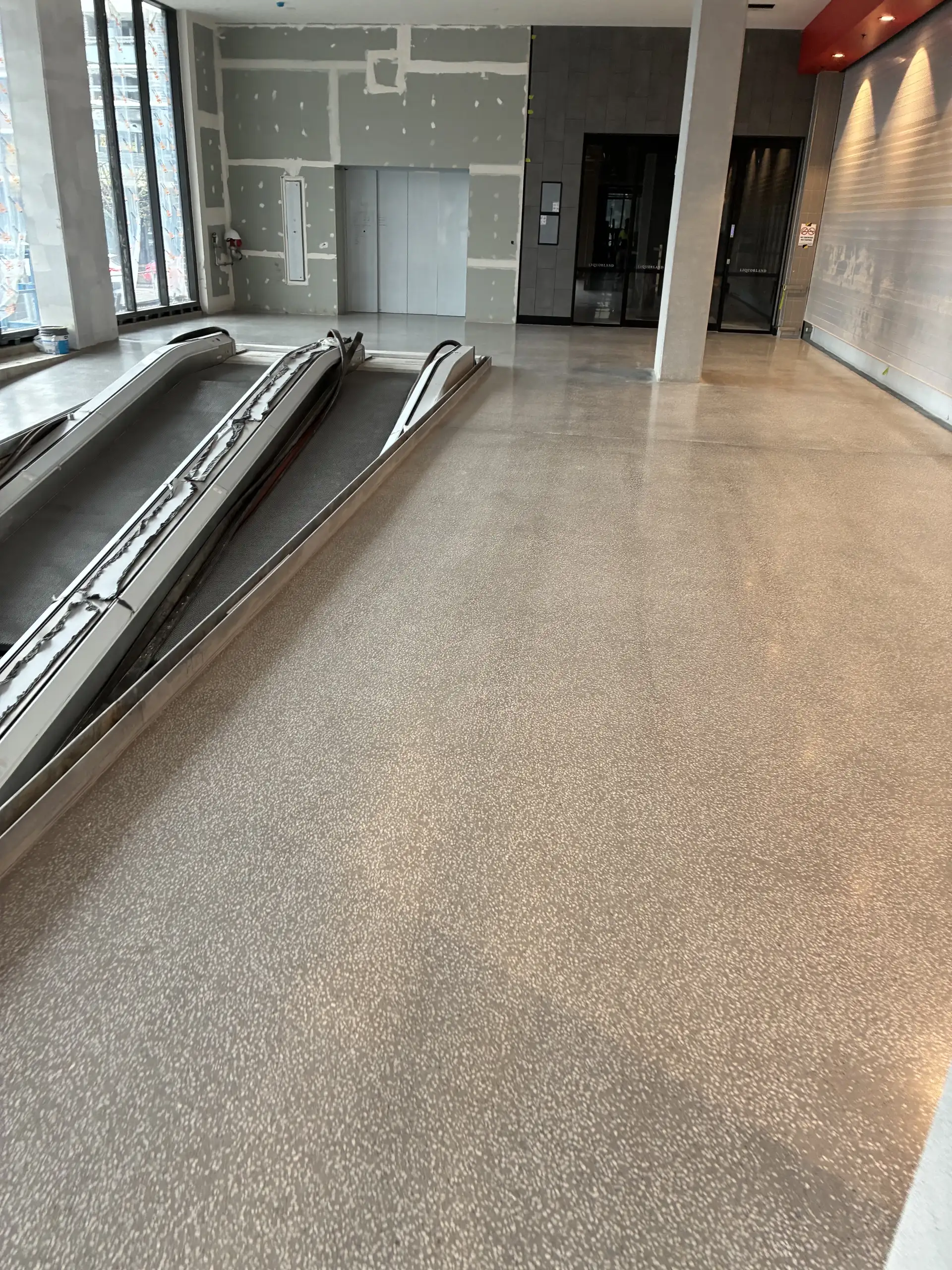 Polished terrazzo-look floor in a commercial retail lobby in Caringbah, with escalators and shopfronts