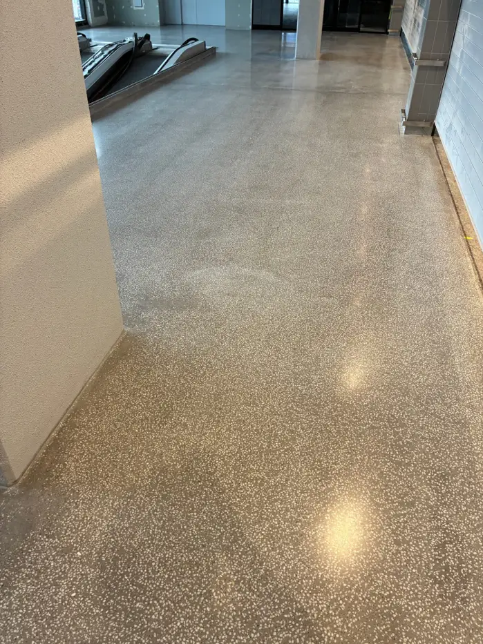 Warm-toned polished terrazzo overlay running past a column at Coles Caringbah