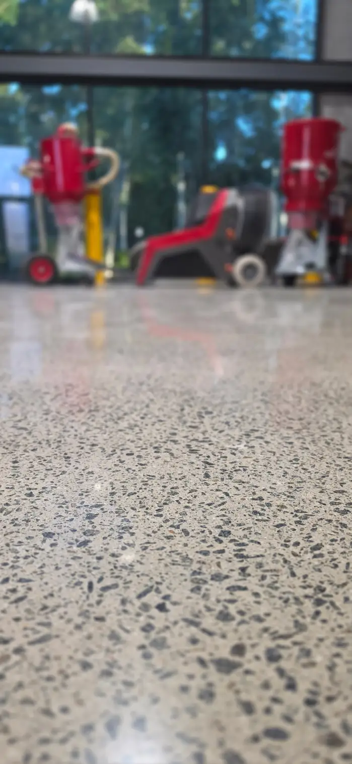 Polished exposed-aggregate concrete floor at the Nextone Lane Cove showroom, with the planetary grinders alongside