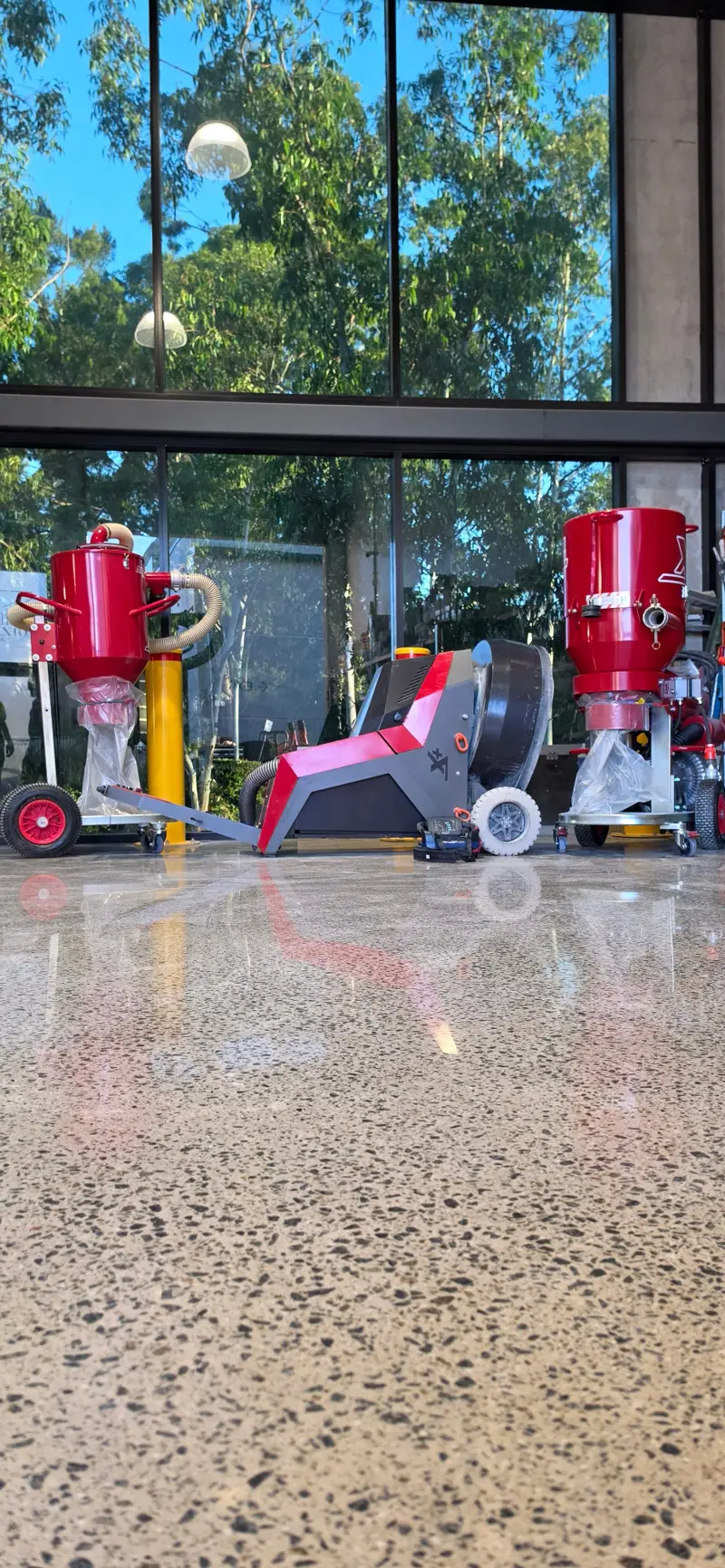 A Nextone planetary grinder parked on a finished, mirror-polished exposed-aggregate concrete floor