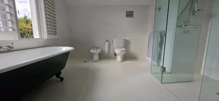 Grout-free microcement bathroom floor with plantation shutters in Manly