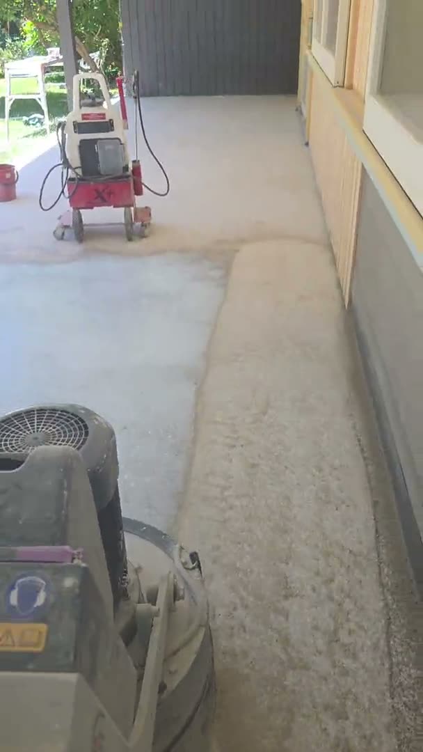 A planetary diamond grinder and dust extractor mid-grind on a Sydney job, with a second machine behind and an unground band of floor still to cut